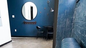 A room with a blue wall, a round mirror, a small table with two chairs, and a blue sofa. - 424 Gold Way - Apt. 404 2Bed/1Bath  (Pittsburgh)