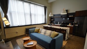 A modern living room with a sofa, coffee table, and a dining area with a kitchen in the background. - 424 Gold Way - Apt. 404 2Bed/1Bath  (Pittsburgh)