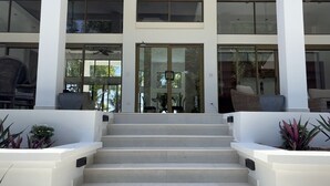 A modern building with a staircase leading to a glass door entrance, large windows, and ceiling fans. - Stunning Oceanfront 4-Bdrm Villa w/ Infinity Pool (Playa Hermosa)