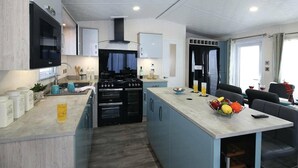 A modern kitchen with a central island, built-in oven, and a dining area with a view.