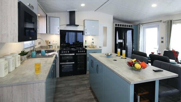 Una cocina moderna con una isla central, horno empotrado y un comedor con vistas.