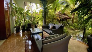 A tropical-themed indoor space with a seating area, a small table, and a water feature.