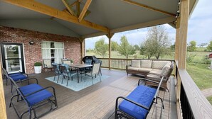 Un patio couvert avec un mur en briques, une table avec des chaises, un canapé et un barbecue.