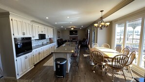 Une cuisine spacieuse avec des meubles blancs, un grand îlot central et un coin repas doté de chaises en bois.