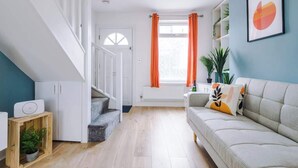 Moderni olohuone, jossa on portaikko, sohva ja ikkuna, jossa on oranssit verhot.