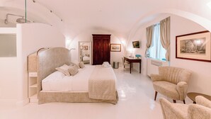 Un dormitorio amplio con una cama grande, dos sillones, un escritorio y un armario.