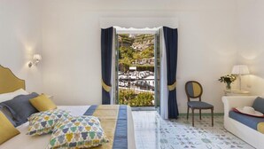 Un dormitorio con cama, una silla, un sofá y vistas a un estacionamiento a través de un ventanal.