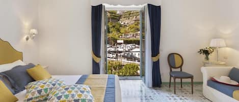 A bedroom with a bed, a chair, a sofa, and a view of a parking area through a glass door.