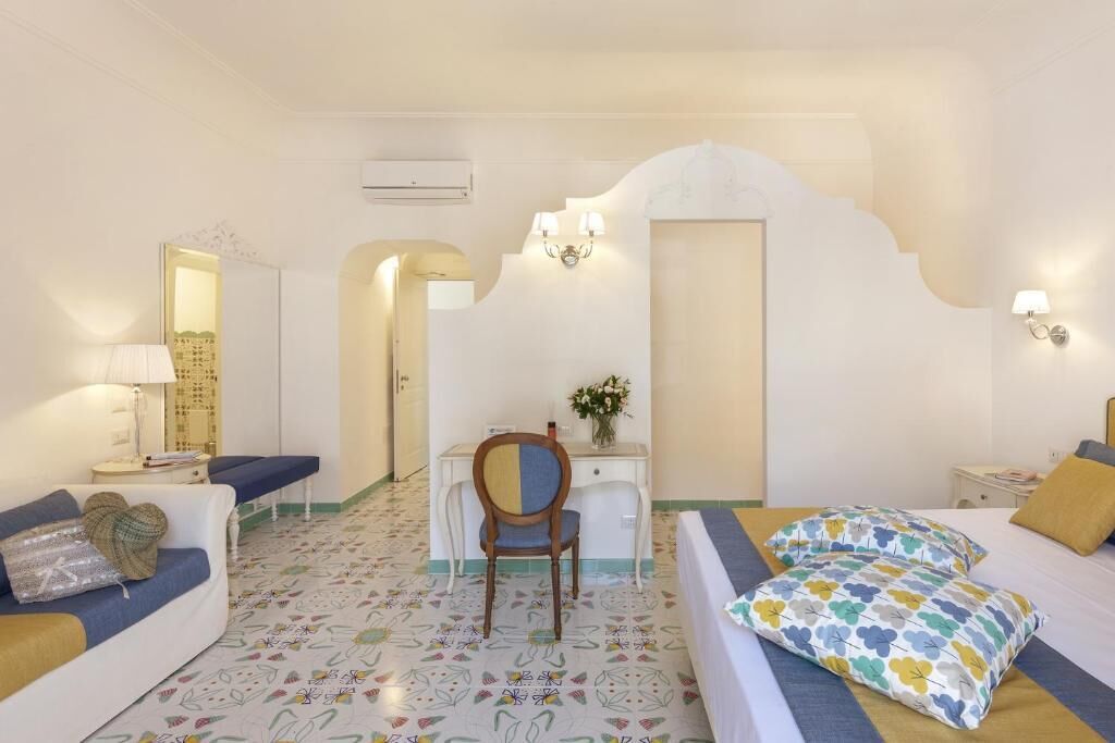 Una habitación de hotel con cama, escritorio, sillón, sofá y espejo.
