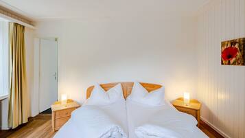 Ein Hotelzimmer mit einem großen Bett, einem Holzkopfende, zwei Nachttischen mit Lampen, einer Tür und einer Wand mit einem gerahmten Bild.