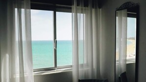 Una habitación con un amplio ventanal con vista a la playa.