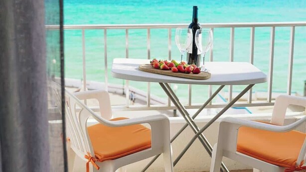 Un balcón con una mesa dispuesta para dos personas, con vistas al mar turquesa.