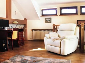 Relax in this inviting living room with a comfortable armchair, wooden desk, and framed artwork.