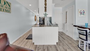 Une cuisine moderne avec des meubles blancs, un îlot central et un élément décoratif suspendu.
