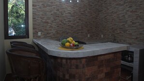Una cocina con encimera de mármol, frutero y salpicadero de ladrillo.