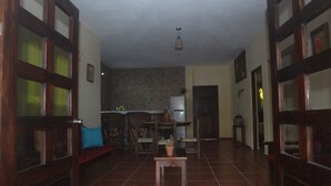 Amplia sala de estar con suelo de baldosas, muebles de madera y una pequeña mesa con planta en maceta.