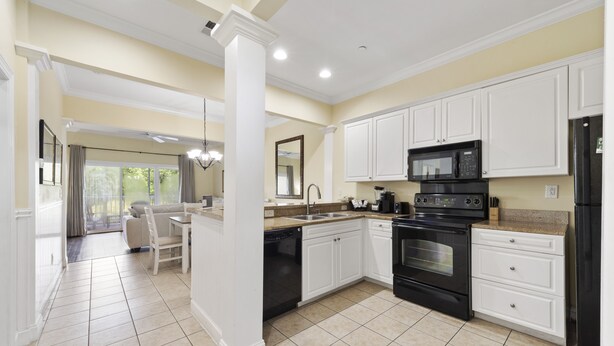 A modern kitchen with white cabinets, a black stove, and a microwave.