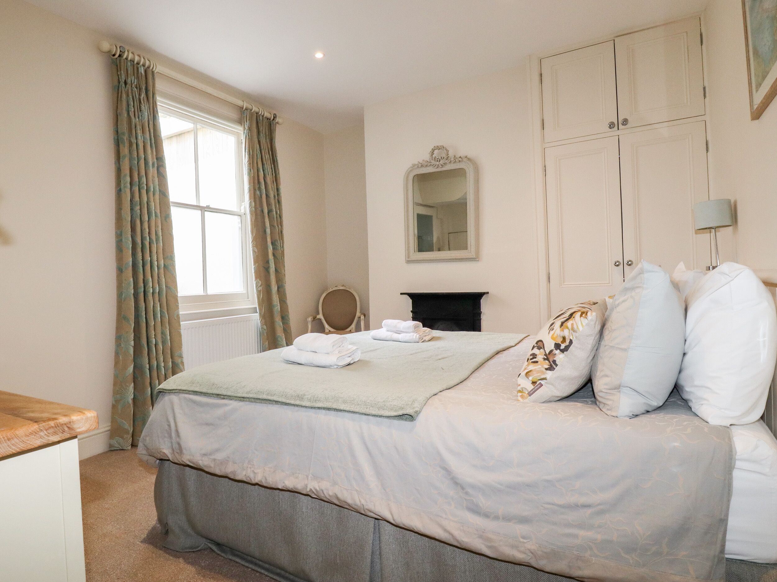 A bedroom with a bed, a dresser, a mirror, and a wardrobe.