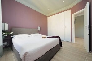 A bedroom with a bed, bedside table, lamp, and wardrobe. - Colosseo Gardens - C13 (Rome)