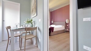 Ein Zimmer mit einem Bett, einem Nachttisch, einem Sessel und einem Schreibtisch mit Stuhl.