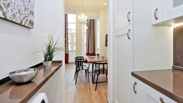 Una cocina moderna con encimera de madera, una zona de comedor con mesa y sillas, y una planta en maceta.