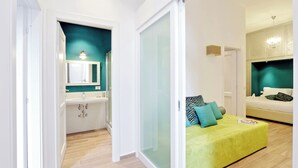 Un dormitorio moderno con cama, mesita de noche y un otoman verde.