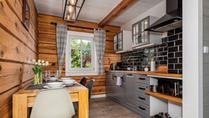 Una cocina moderna con paredes de madera, un comedor con una mesa dispuesta para cuatro personas y una ventana con cortinas.