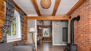 Una habitación acogedora con un sofá gris, vigas de madera, una pared de ladrillo y una estufa negra.