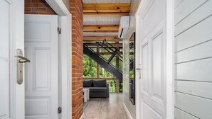 Un couloir avec des portes blanches, un mur en briques et un plafond en bois.