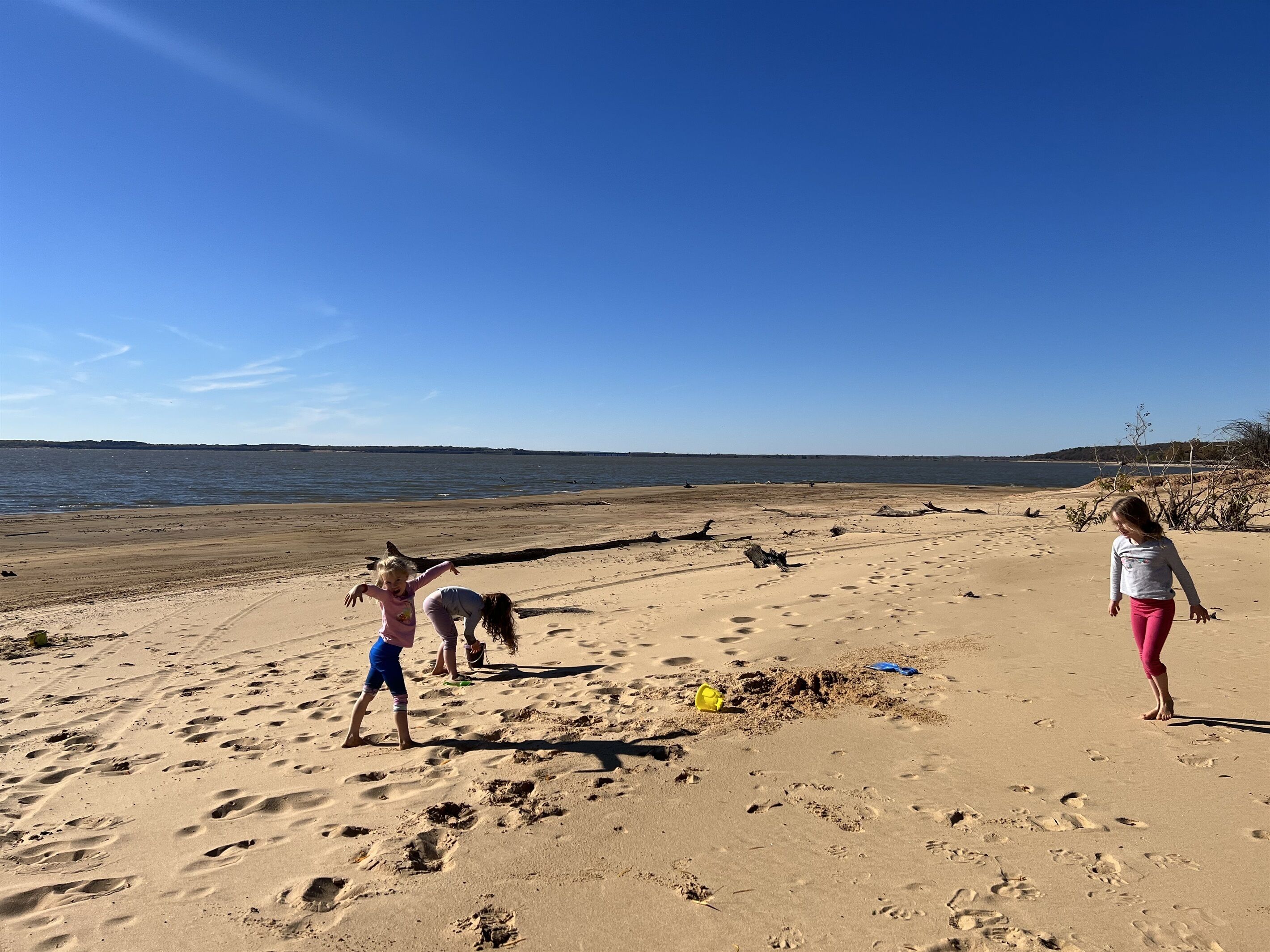 En sandstrand med fotspår, en klar himmel och ett lugnt hav i bakgrunden.