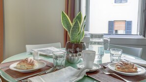 A breakfast table with croissants, a potted plant, and water glasses.