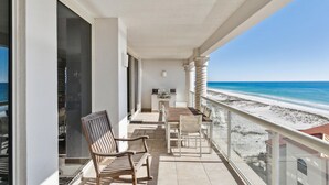 Un balcón con vista a la playa, una mesa con sillas y un banco.