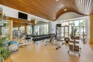 Une salle de sport équipée de matériel d’exercice, de miroirs et de grandes fenêtres.