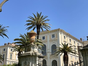 Un bâtiment historique à l’architecture classique, avec des fenêtres en arc et une cour intérieure dotée d’une fontaine.