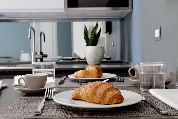 A breakfast setting with croissants, a cup, and a glass of water on a table.