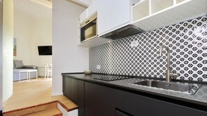 A modern kitchen with a black and white patterned backsplash, a stainless steel sink, and a microwave above the counter.