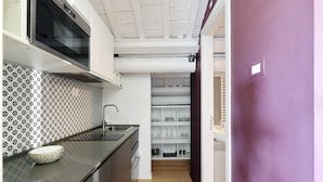 A modern kitchen with a patterned backsplash, a built-in oven, and a wooden floor.