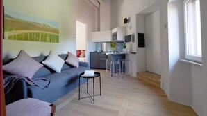 A modern living room with a sofa, a small table, and a kitchen area with a dining table and chairs. - Il mulino di Trastevere - G4 (Rome)