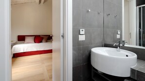 A modern bathroom with a white sink, dark tiled walls, and a large mirror. - Il mulino di Trastevere - G4 (Rome)