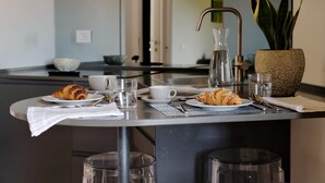 A modern kitchen with a dining table set for breakfast, including croissants, coffee cups, and a water pitcher. - Il mulino di Trastevere - G4 (Rome)