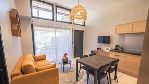 A modern kitchen with a dining table and chairs, a sofa, a TV, and a coffee machine.