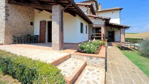 Una casa de dos pisos con patio, mobiliario exterior y jardín.