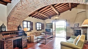Una sala de estar rústica con paredes de ladrillo visto, un escritorio de madera, un sofá y una chimenea.