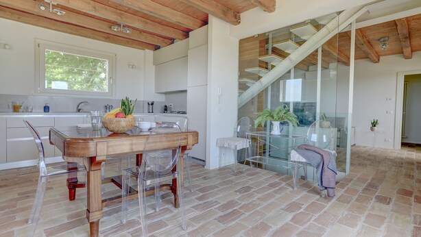 Une cuisine moderne avec une table et des chaises en bois, une grande fenêtre et un escalier menant à un étage supérieur.