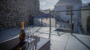 Un mur de pierres, une bouteille de champagne et des verres sur une table.