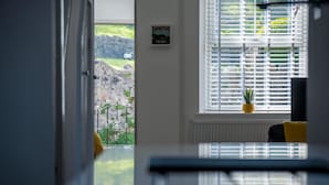 Une pièce avec vue sur un paysage rocheux, visible à travers une fenêtre munie de stores.