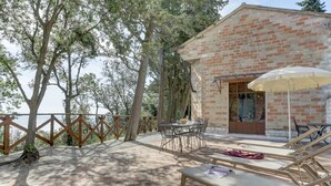 A patio area with a brick building, outdoor furniture, and a view of the sea.
