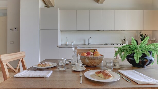 Ein Essbereich mit einem Holztisch, gedeckt für das Frühstück, inklusive Croissants und einer Obstschale.