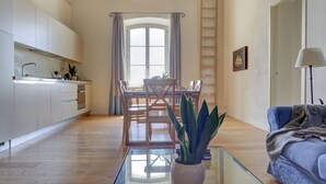 Eine moderne Küche mit weißen Schränken, einem Esstisch mit Stühlen, einem Blumentopf und einem Glastisch.
