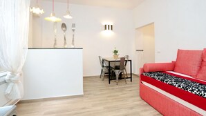 Un salon moderne avec un canapé rouge, une table à manger et des chaises, ainsi que des luminaires suspendus.